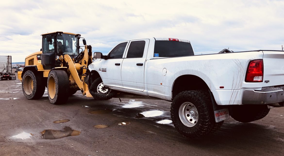 Heavy machinery towing a large white truck